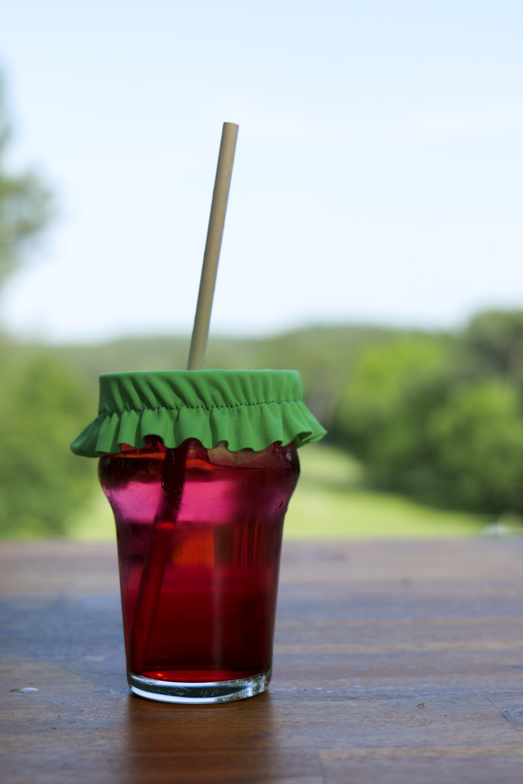 Azala — verre de boisson rouge couvert d'un couvre-verre vert en terrasse