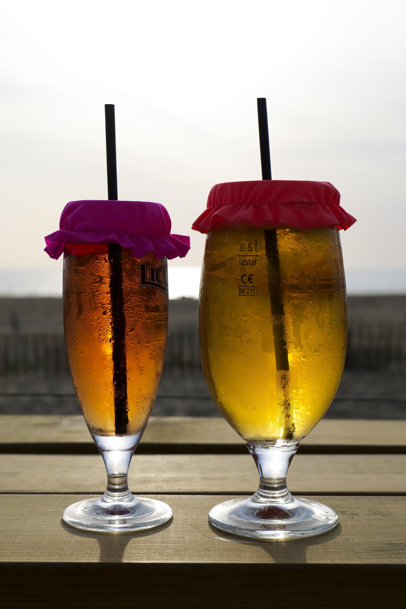 Azala — deux verres à bière coiffés de couvre-verres rouges au soleil couchant