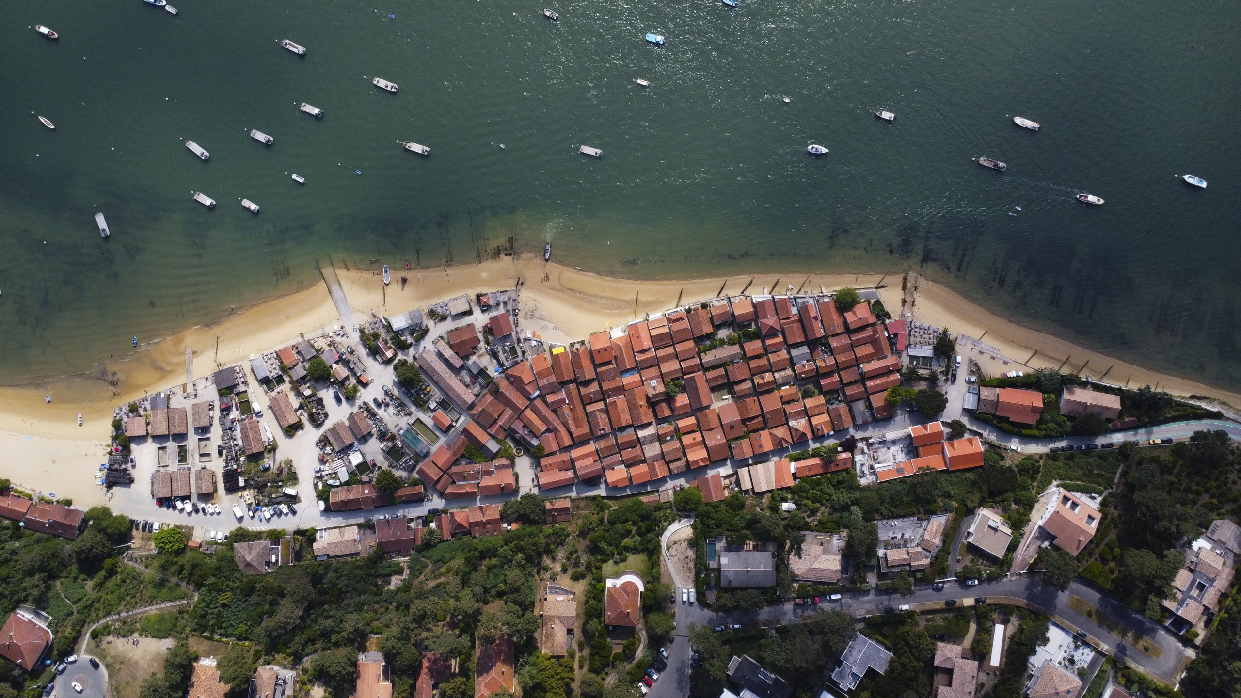 Vue d'en haut — vue aérienne par drone d'un village côtier aux toits de tuiles face à une baie